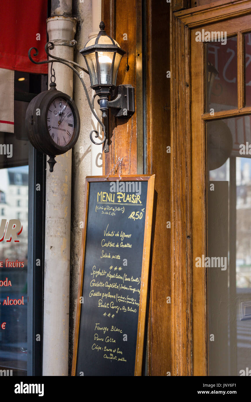 Parigi, Francia - 29 Febbraio 2016: orologio, lampada e lavagna menu al di fuori di un ristorante in rue Jean de Bellay, Ile Saint-Louis, Parigi, Francia. Foto Stock
