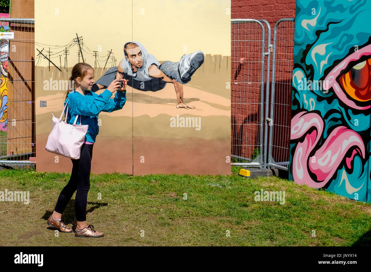 Bristol, Regno Unito. 31 Luglio, 2017. Una giovane ragazza è raffigurato nella North Street park di Bedminster come lei prende una fotografia di illustrazione creata per il festival Upfest. Upfest che avviene nel corso di tre giorni è il più grande d'Europa libera, street art & graffiti festival e ora è nel suo nono anno. Credito: lynchpics/Alamy Live News Foto Stock