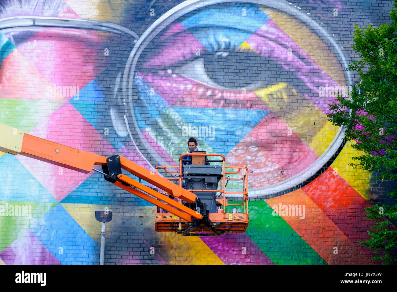 Bristol, Regno Unito. 31 Luglio, 2017. Artista Eduardo Kobra è raffigurato come egli applica i tocchi finali al suo formato gigante John Lennon murale sul lato della fabbrica di tabacco in Bedminster per Upfest 2017. Upfest che avviene nel corso di tre giorni è il più grande d'Europa libera, street art & graffiti festival e ora è nel suo nono anno. Credito: lynchpics/Alamy Live News Foto Stock