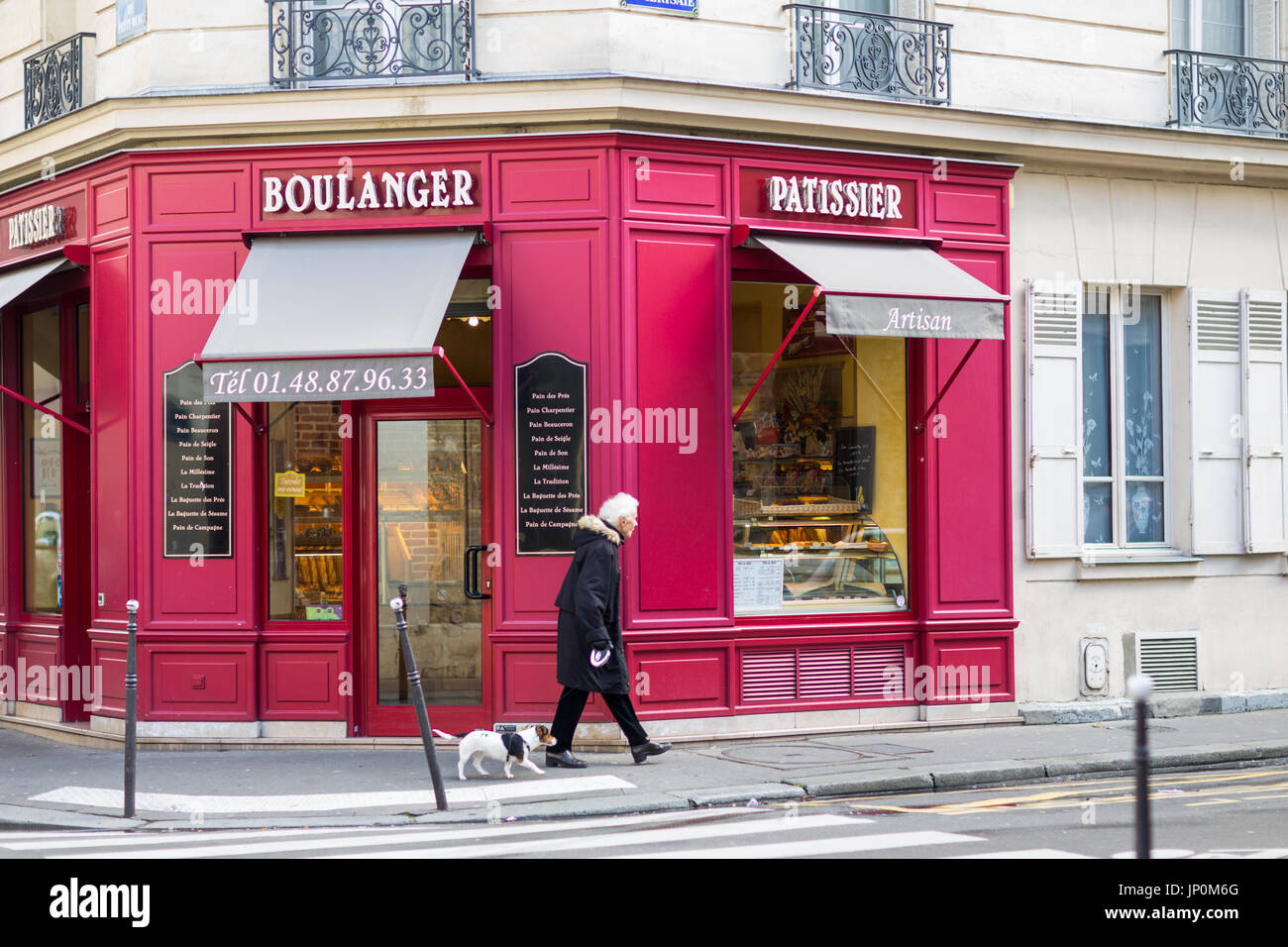 Parigi, Francia - 2 Marzo 2016: Donna cammina il suo cane rosso passato panetteria e pasticceria all' angolo di rue du Petit Musc e rue de la Cerisaie nel Marais, Parigi. Foto Stock