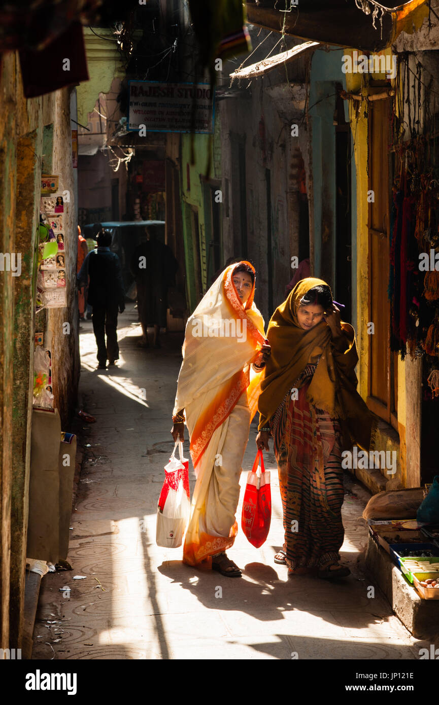 Due donne camminare lungo uno stretto vicolo di Varanasi Foto Stock