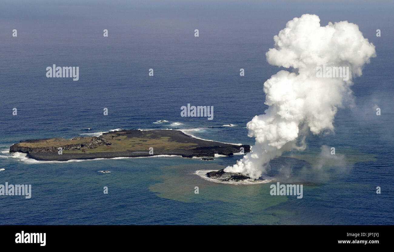 Isola HACHIJO, Giappone - Foto scattata da un Kyodo News aereo su nov. 21, 2013, mostra fumo che sale da un nuovo isolotto creato da un sottomarino recente eruzione vulcanica vicino Nishinoshima Island (L) nel Pacifico, un isolotto disabitato in Ogasawara catena di isole, alcune mille chilometri a sud di Tokyo. Secondo la Japan Meteorological Agency, la nuova zona della terra non può essere chiamato un'isola ancora, perché potrebbe sommergere sotto il mare se l'attività vulcanica subisce un arresto. (Kyodo) Foto Stock