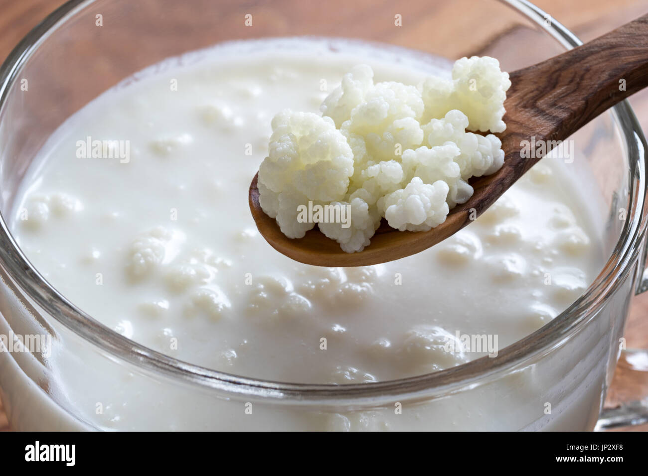 Il Kefir grani su un cucchiaio di legno al di sopra di un barattolo di  latte in casa il kefir Foto stock - Alamy