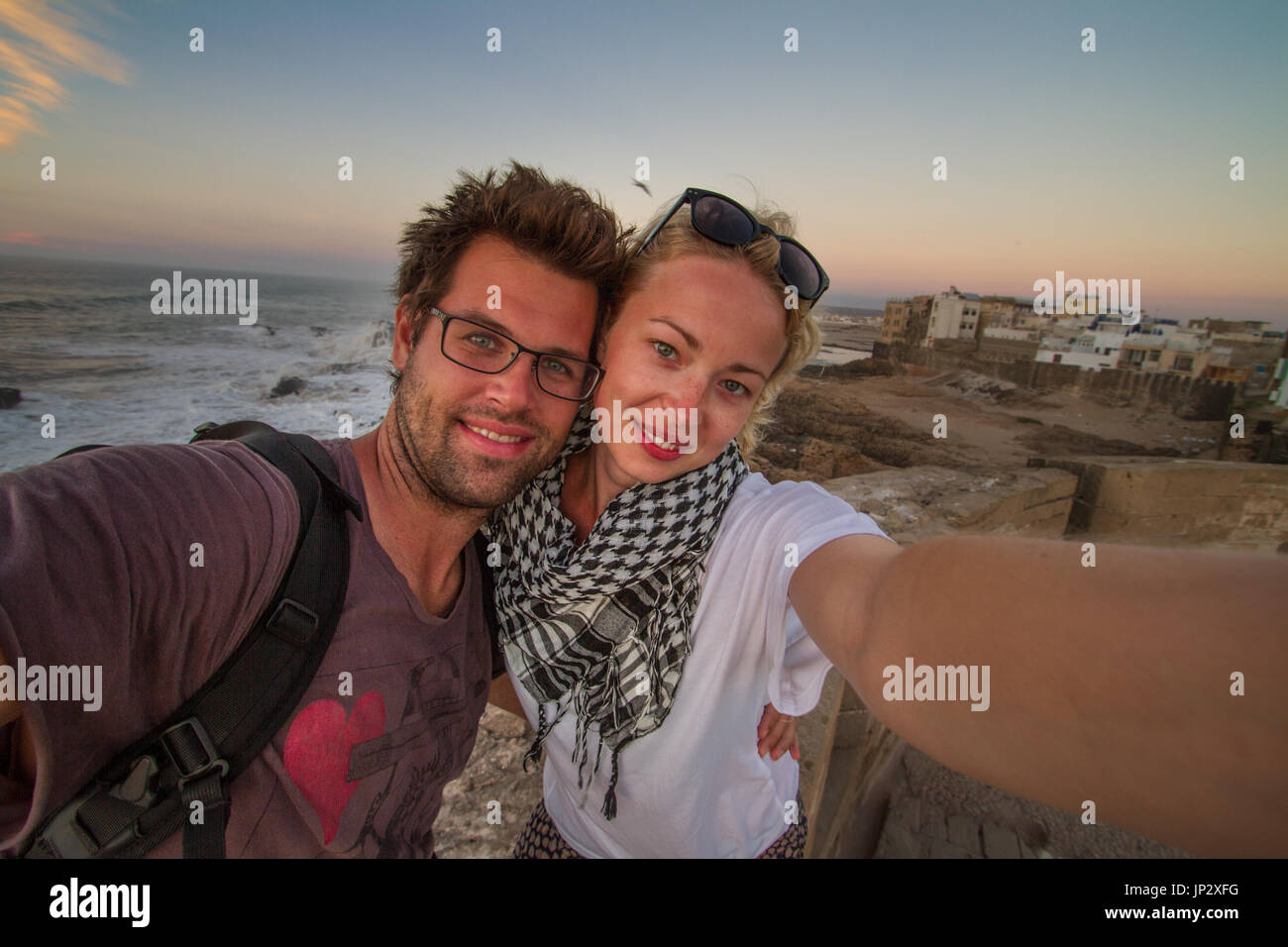 Coppia di viaggiatori tenendo selfie sulla città fortezza di parete Essaouira, Marocco. Foto Stock