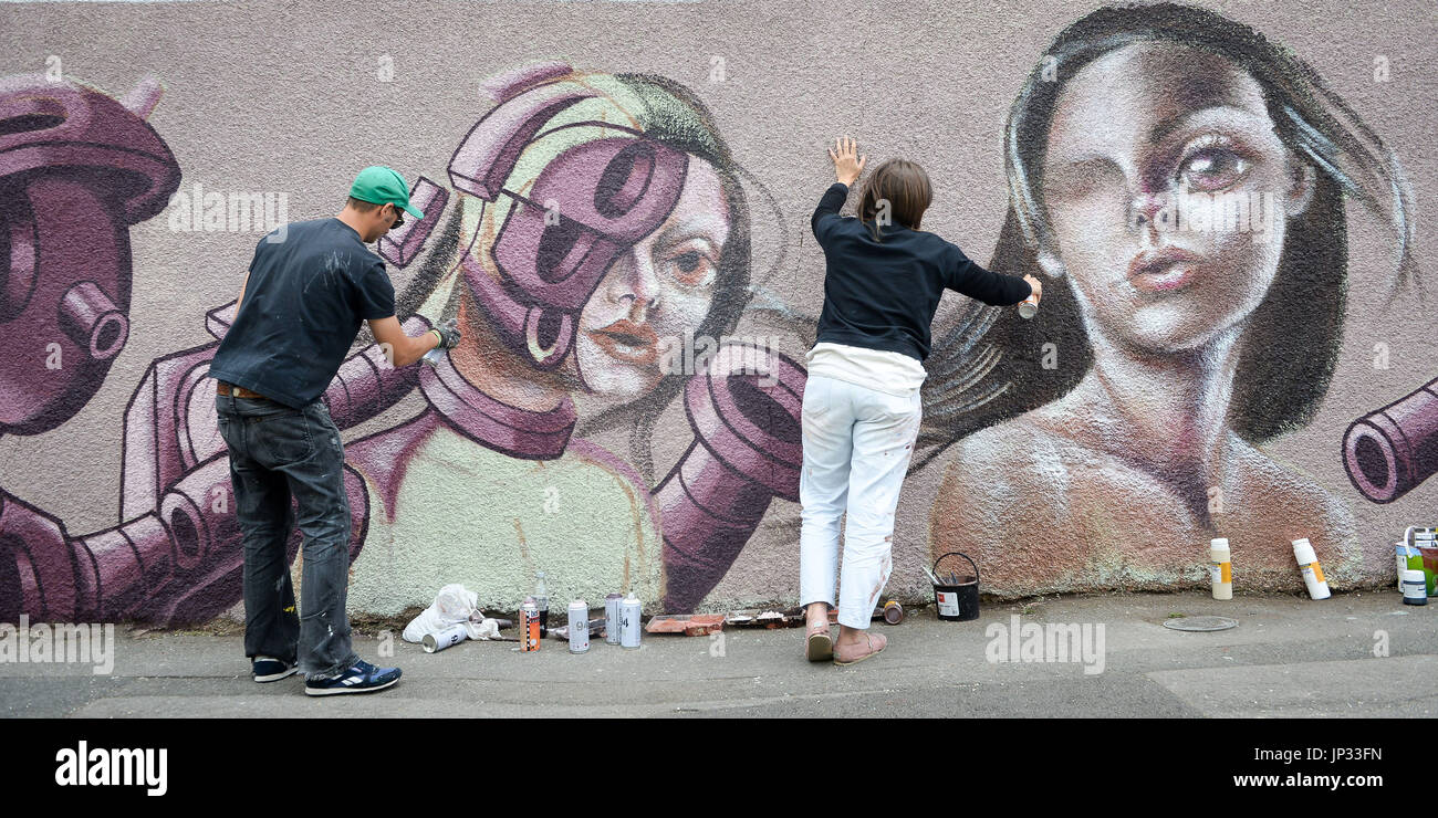 Artisti di Graffiti "Età Age', a sinistra e a "Caro Pepe' opera su un livello strada pezzo su un giardino a parete come essi prendono parte in Upfest, un arte di strada e graffiti festival di Bristol. Foto Stock