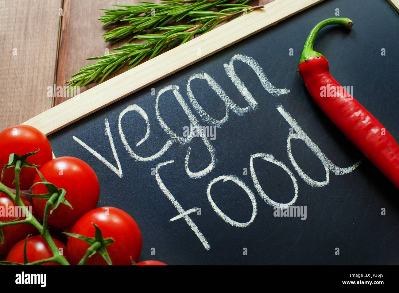 Cibo Vegan chalk iscrizione. i pomodori, aglio, carote, cetriolo, pepe, rosmarino intorno all iscrizione top view Dieta e un sano concetto Close up Foto Stock