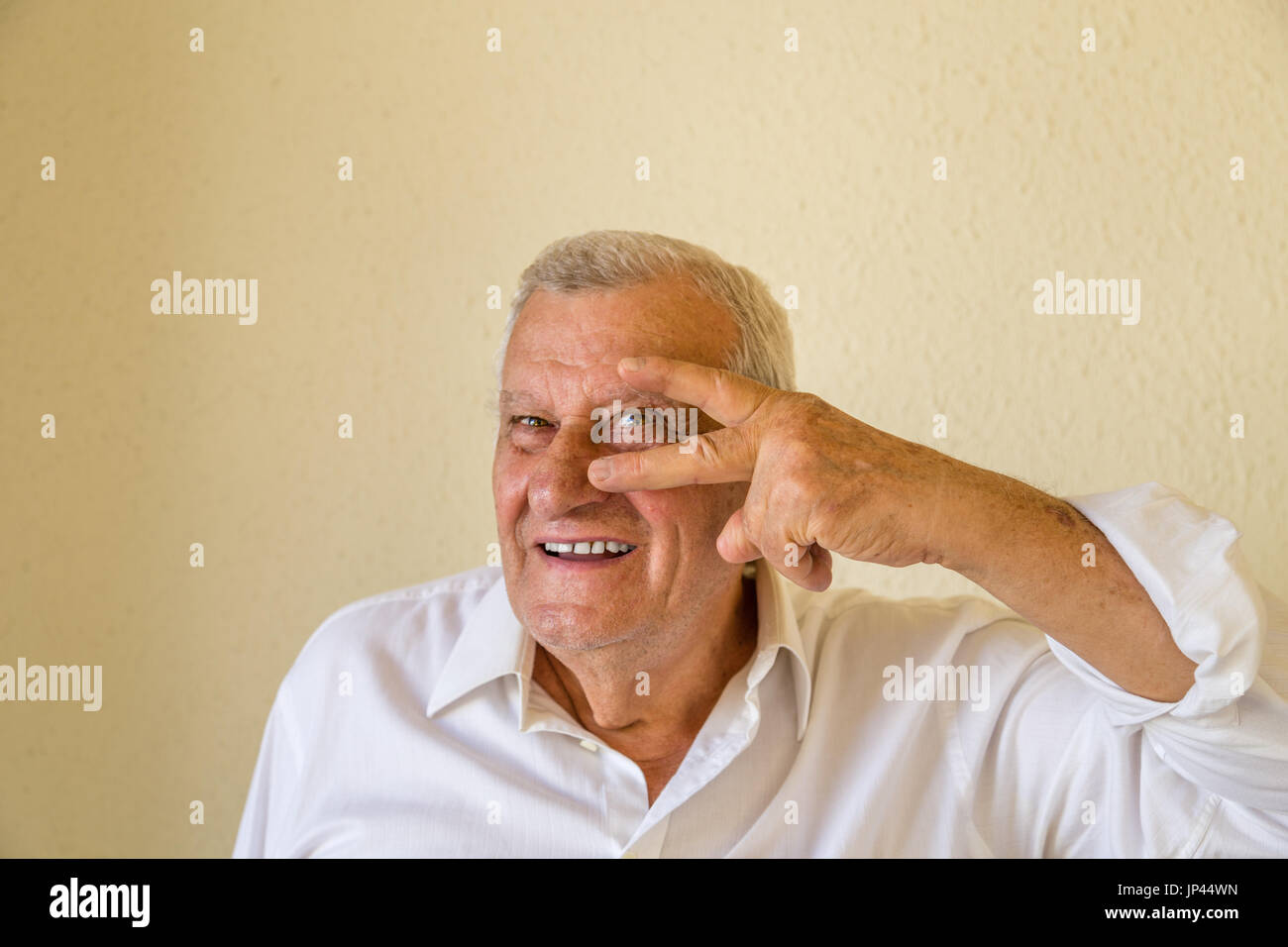 Vecchio modello maschio felice che mostra il gesto rock su sfondo giallo parete con spazio vuoto copia Foto Stock