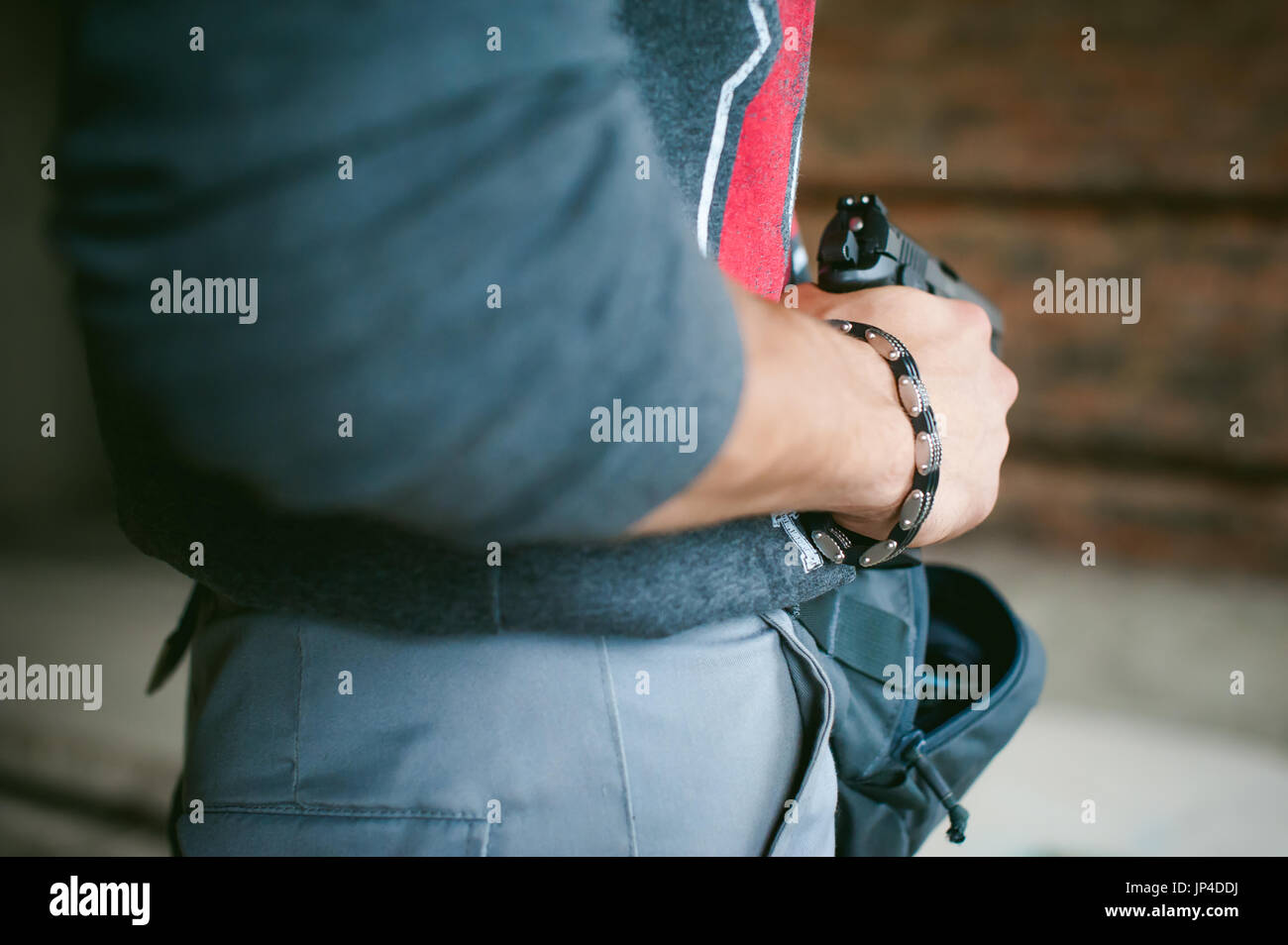 Uomo tira una pistola fuori della sua borsa, tenendolo in mano Foto Stock