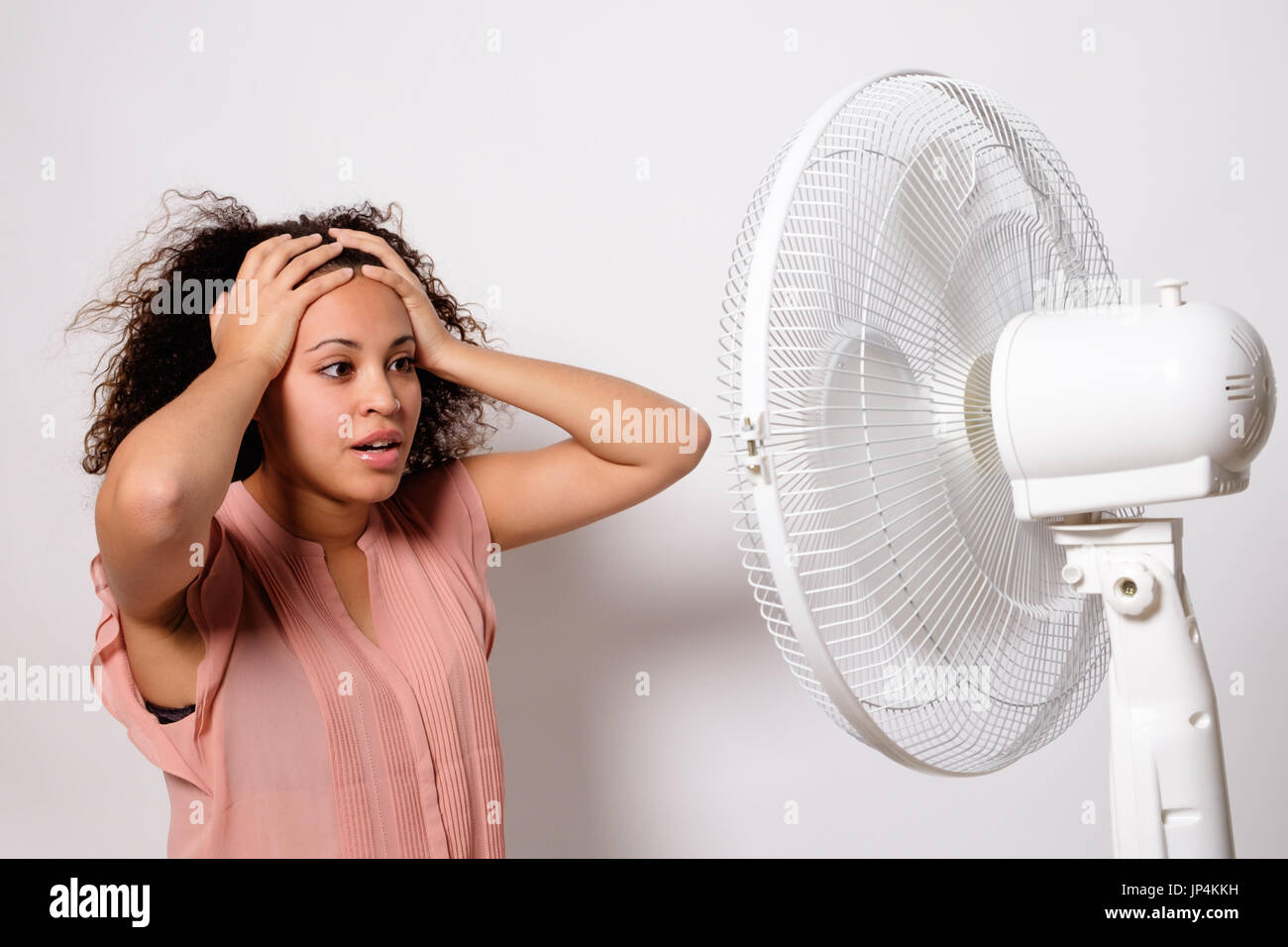 Nero donna sensazione calda e seduto davanti a un ventilatore elettrico  Foto stock - Alamy