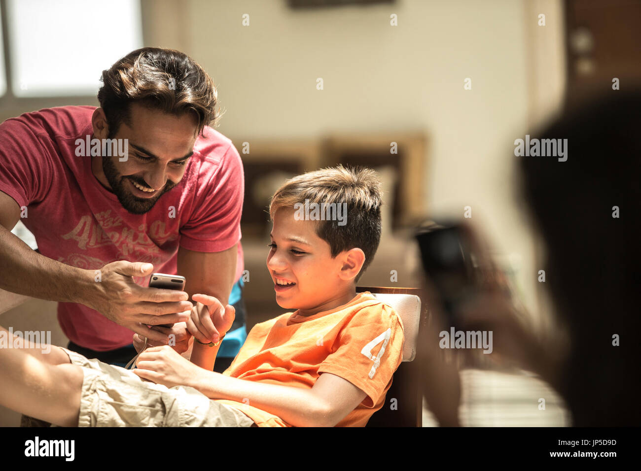 Un uomo e un ragazzo alla ricerca di un telefono cellulare schermo. Foto Stock
