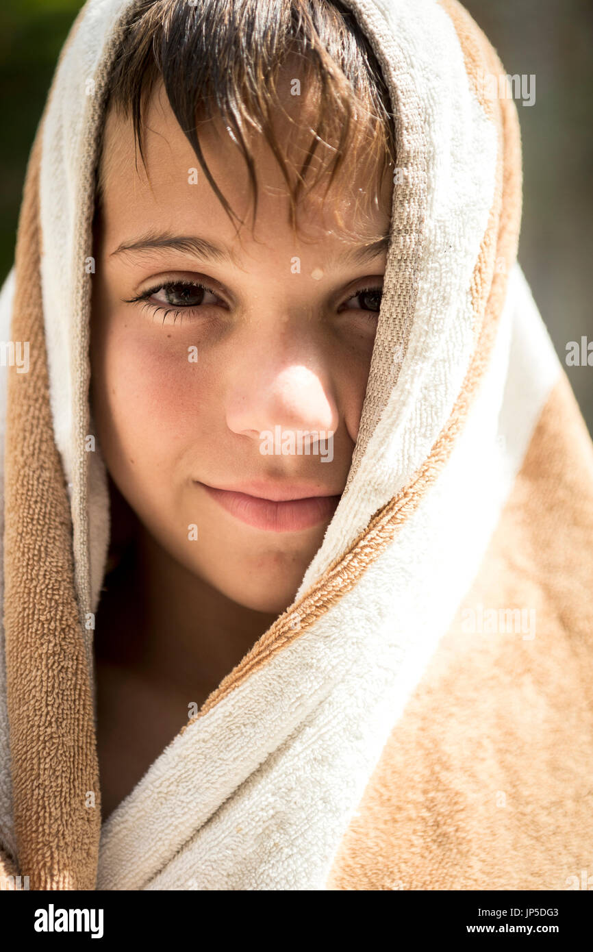 Close up di un ragazzo avvolto in un asciugamano sorridente nell'inquadratura. Foto Stock