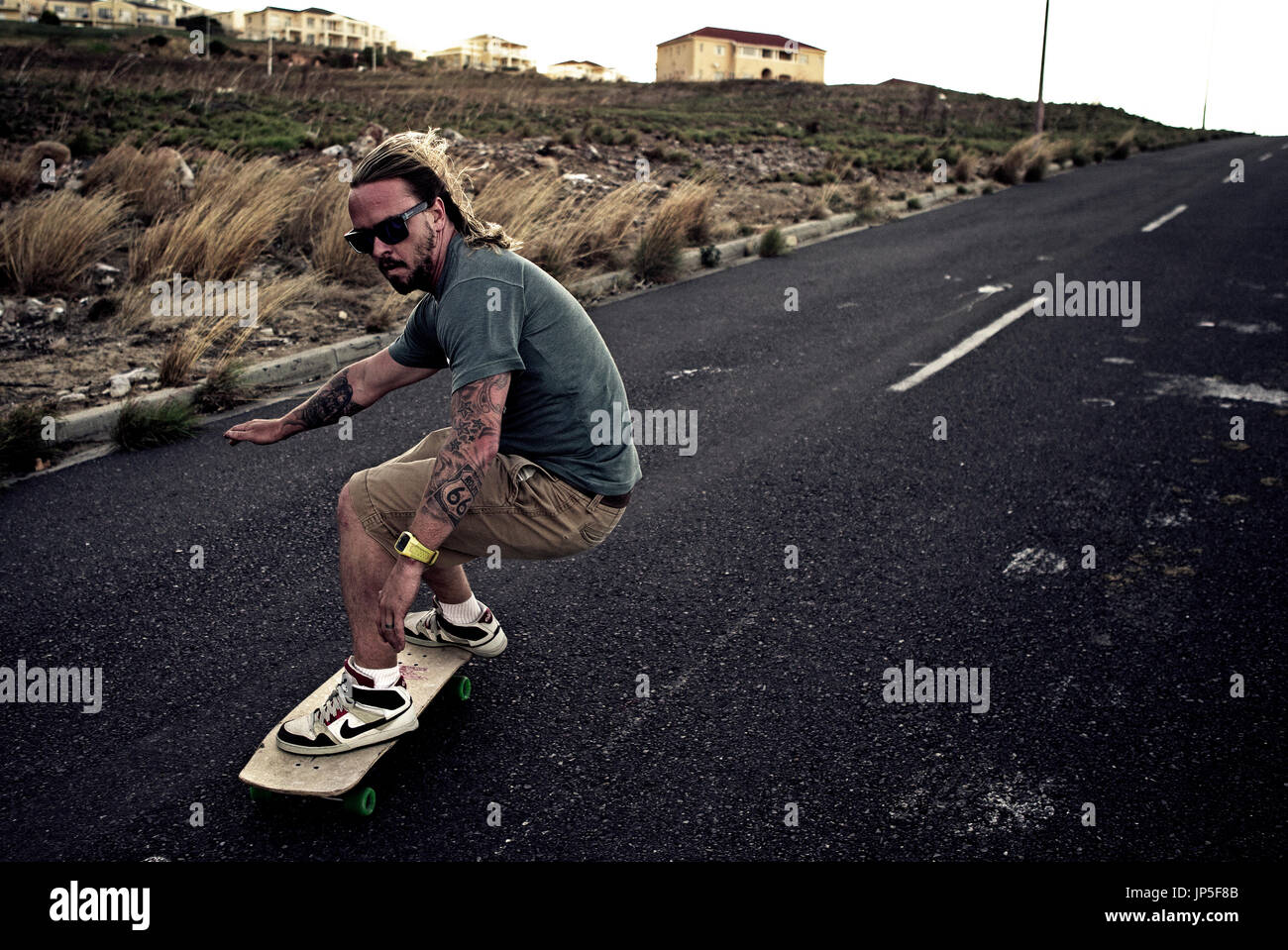 Un giovane uomo lo skateboard su una strada. Foto Stock