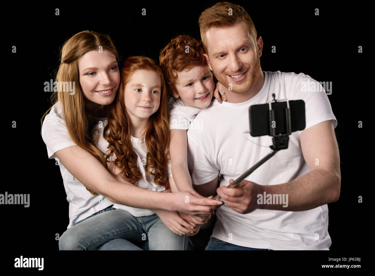 La famiglia felice tenendo selfie sullo smartphone isolato su nero Foto Stock