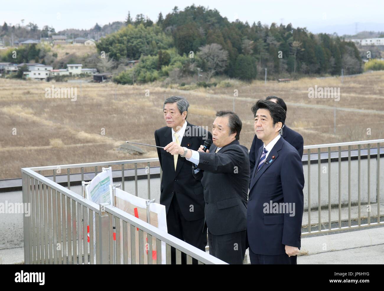 Primo Ministro giapponese Shinzo Abe (R) sorge sul tetto del Futaba storico palazzo del governo nella prefettura di Fukushima il 1 marzo 2015, come egli è informato dal sindaco Shiro Izawa (C) su un sito di stoccaggio provvisorio strutture per radioattivamente terreno contaminato e altri rifiuti generati nel lavoro di pulitura dopo il 2011 catastrofe nucleare. (Piscina Foto di Jiji Press)(Kyodo) ==Kyodo Foto Stock