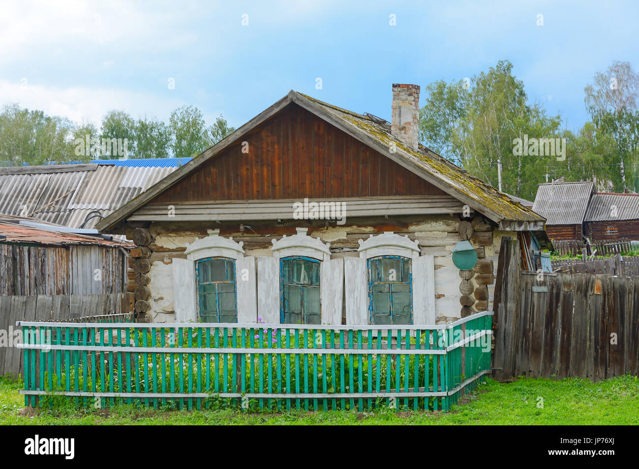 Vecchia casa in legno con un piccolo giardino in un paesino siberiano Foto Stock