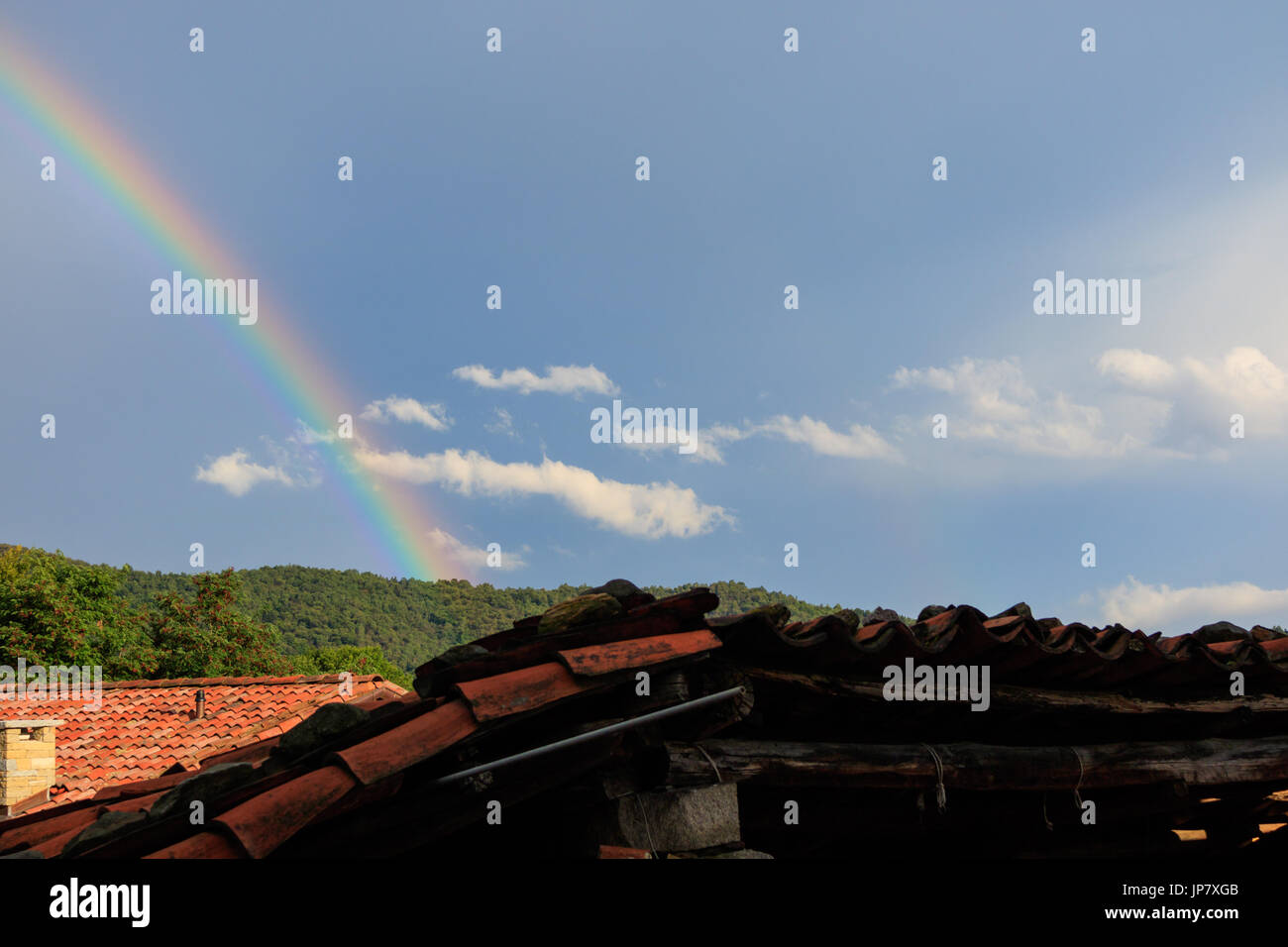 Scena con un naturale fenomeno di arcobaleno, cielo blu su una foresta di alberi in montagna Foto Stock