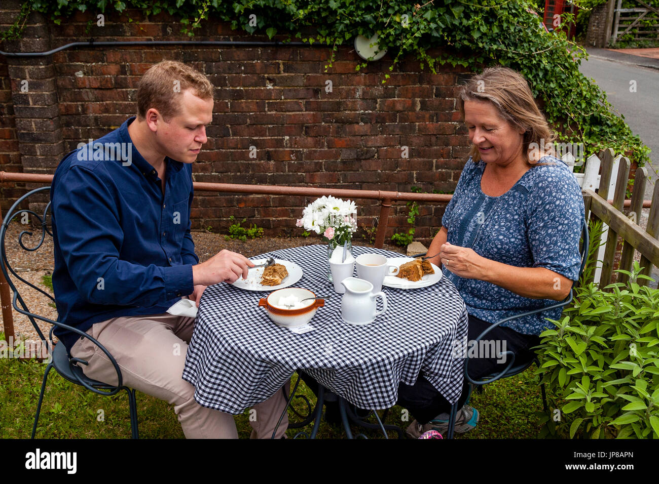 Una madre e figlio gustare tè e torte in un bar giardino, Fulking, Sussex, Regno Unito Foto Stock