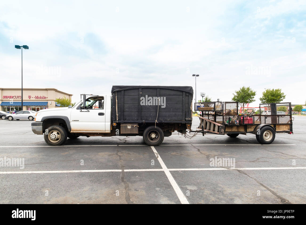 Una Chevrolet pickup truck con sponde laterali con un programma di utilità rimorchio pieno di prato attrezzature di cura parcheggiato in un parcheggio nella città di Oklahoma, Oklahoma, Stati Uniti d'America. Foto Stock