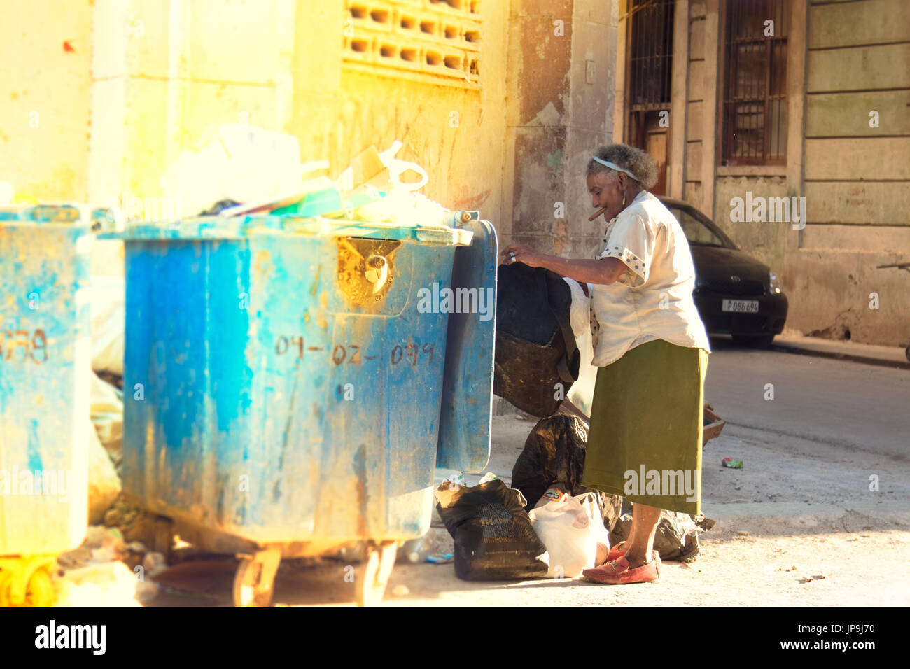 Una vecchia donna cubana fuma un sigaro mentre raccogliendo recyclables a l'Avana, Cuba. Foto Stock