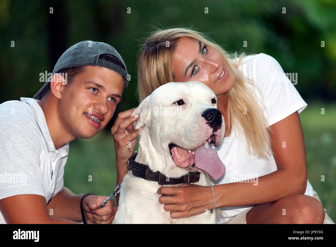 La giovane coppia in amore si rilassa in natura con il loro cane - Dogo Argentino. Essi godere insieme in una splendida e soleggiata giornata estiva Foto Stock