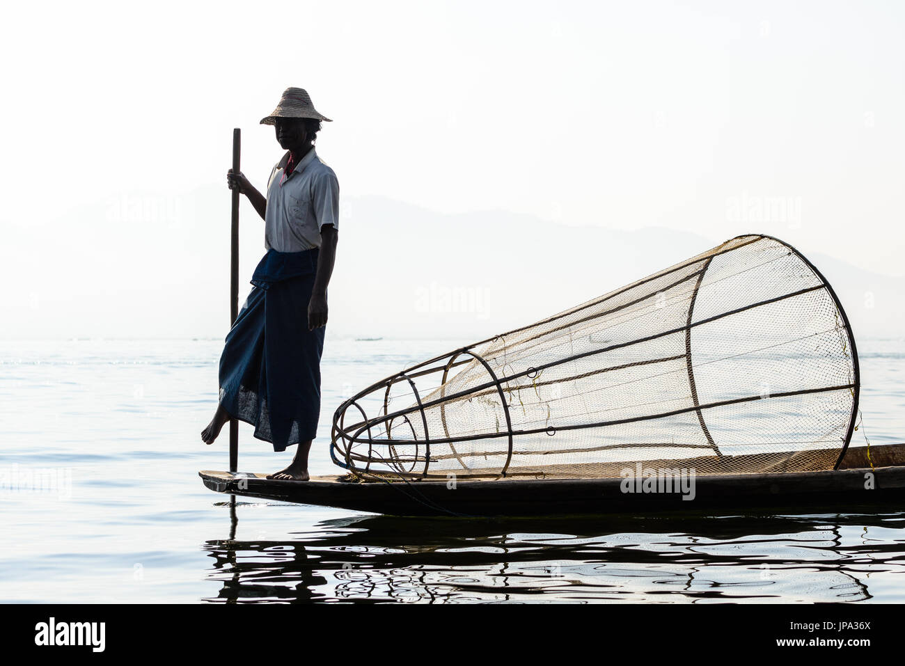 Lago Inle, MYANMAR - 15 febbraio 2014: pescatore birmano sulla barca di bambù per la cattura di pesce in modo tradizionale con la rete a mano. Lago Inle, Myanmar (Birmania Foto Stock