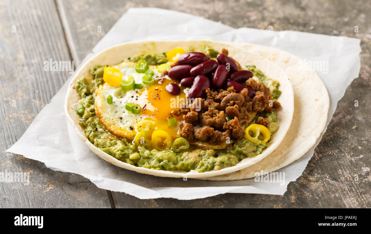 La colazione taco con il guacamole, soleggiato lato fino all'uovo, carne di soia e i fagioli borlotti Foto Stock