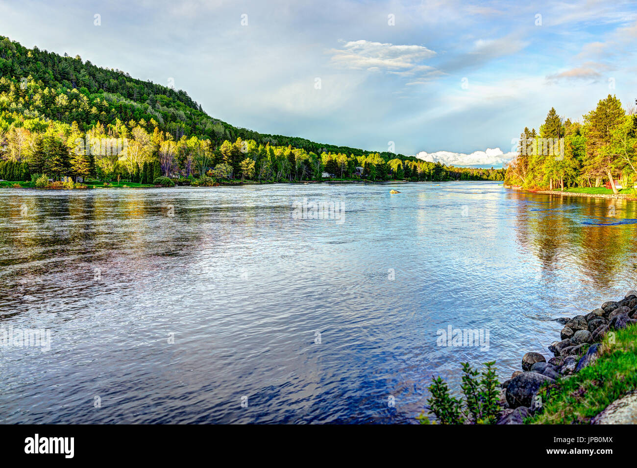 Chicoutimi nel fiume Saguenay, Quebec, Canada con il Riverfront case e foresta durante il tramonto Foto Stock