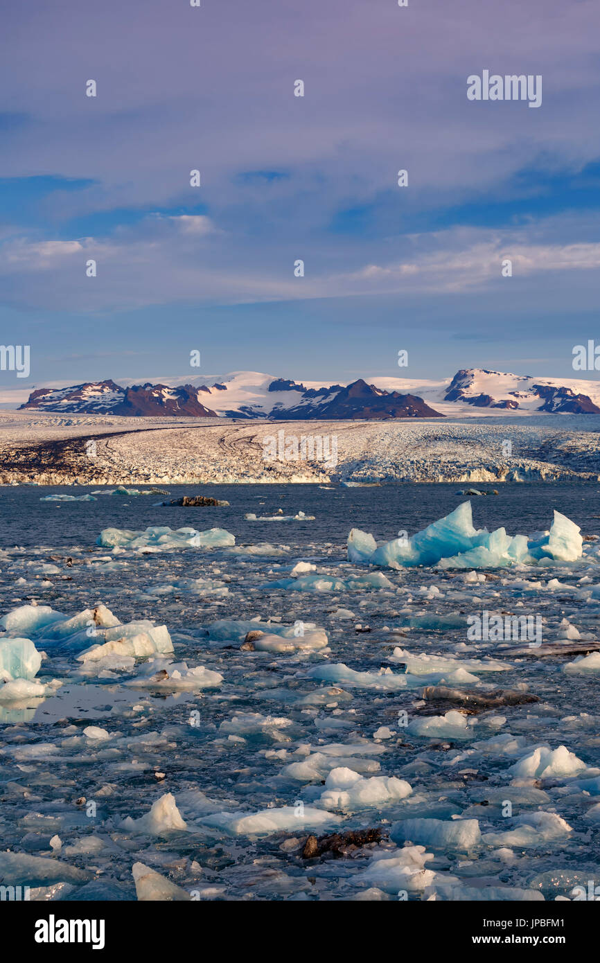 Ghiaccio, iceberg, bordo meridionale del ghiacciaio Vatnajokull e montagne coperte di neve, Jokulsarlon laguna glaciale, Vatnajokull National Park, Islanda Foto Stock