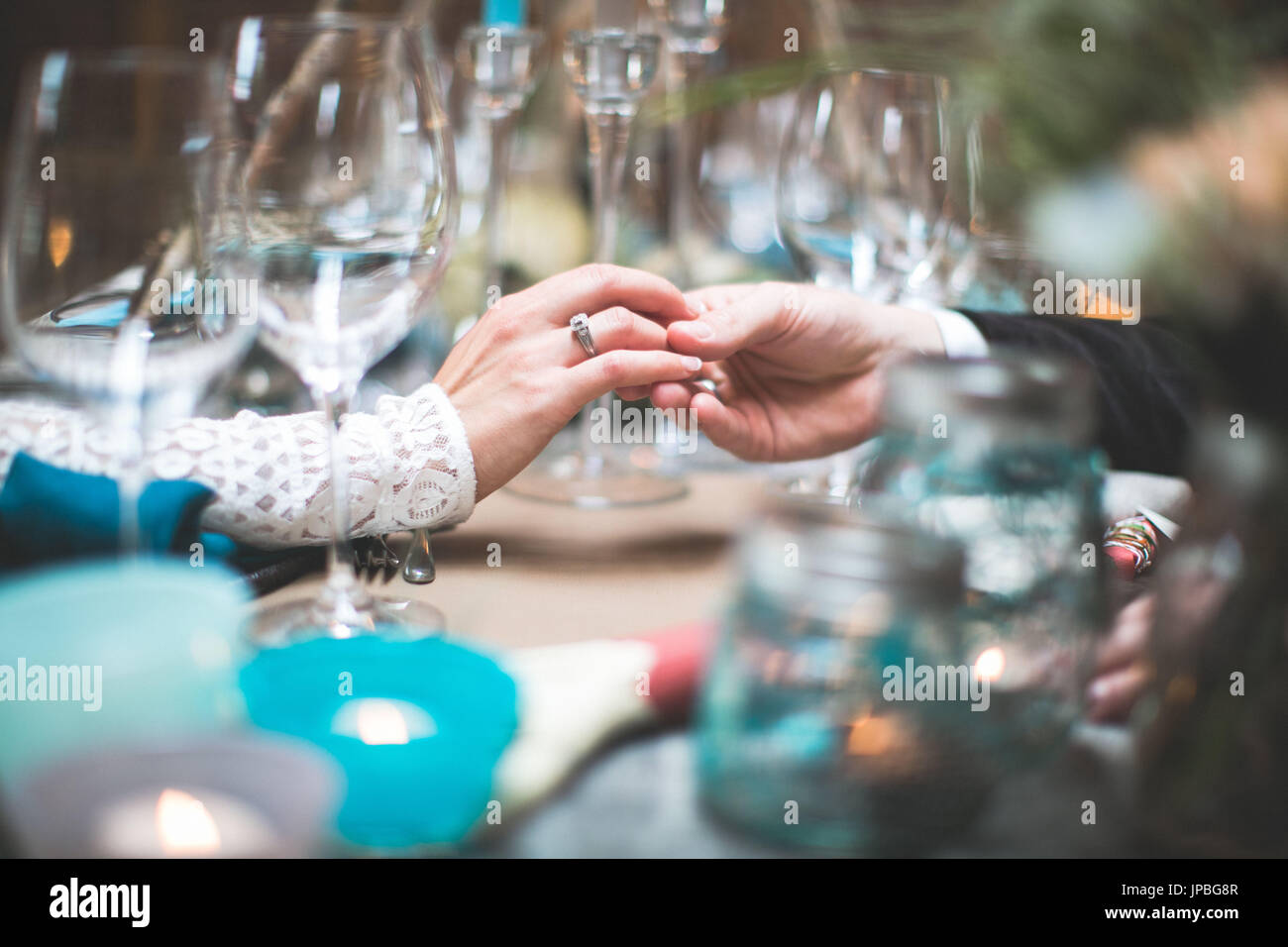 Sposa e lo sposo a coperti da tavola al matrimonio indiano, mani, touch, tenerezza, close up Foto Stock