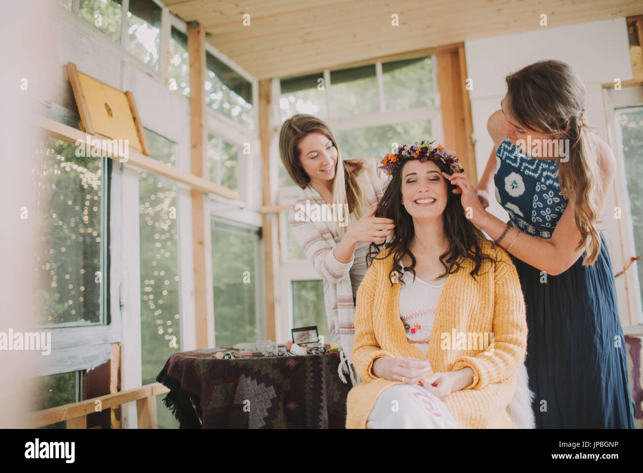 Nozze alternative, preparazione, amici decorare sposa con ghirlanda floreale Foto Stock