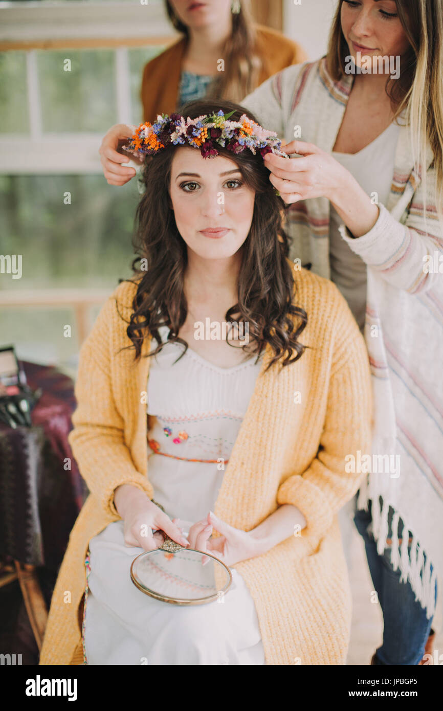 Nozze alternative, preparazione, fidanzate decorare sposa con ghirlanda floreale Foto Stock