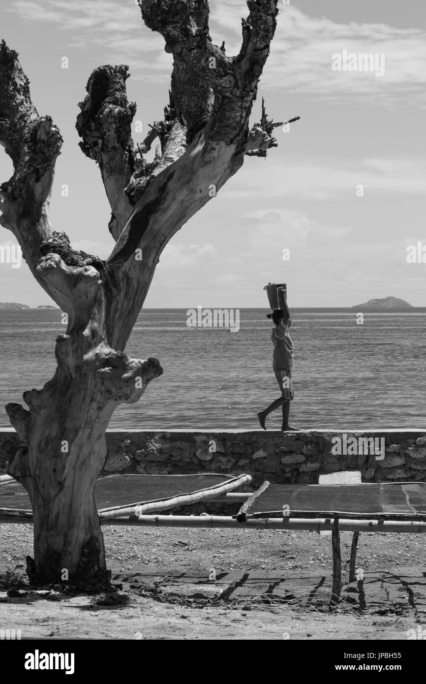 Bambino al lavoro per aiutare i pescatori, Rinca, Indonesia, Komodo, UNESCO patrimonio mondiale Foto Stock