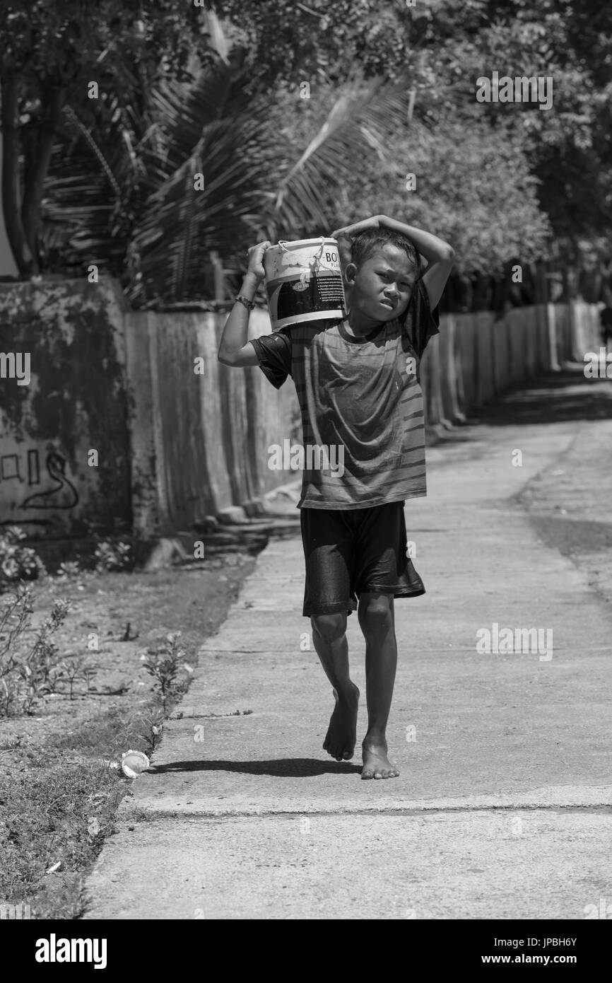 Bambino al lavoro per aiutare i pescatori, Rinca, Indonesia, Komodo, UNESCO patrimonio mondiale Foto Stock