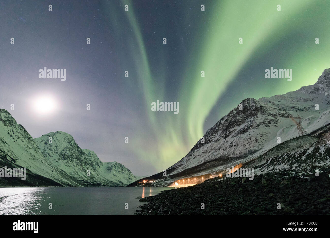 Le luci del nord e la luna riflessa nel mare di illuminare la cima innevata dell'Lyngseidet Alpi Lyngen Tromsø Norvegia Europa Foto Stock
