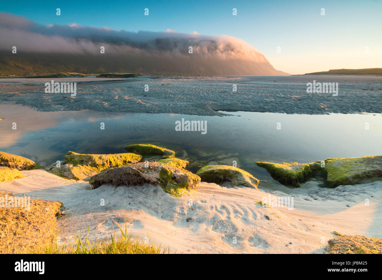 Il sole di mezzanotte è riflessa nel freddo mare in estate Fredvang Moskenesøya Nordland county Isole Lofoten in Norvegia Europa Foto Stock
