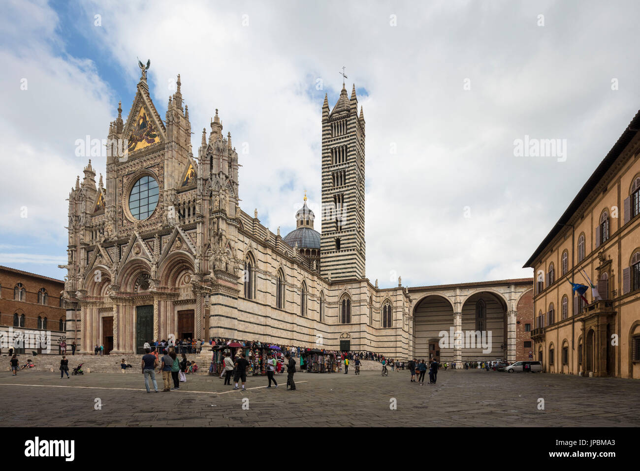 La bianca facciata in marmo e le decorazioni artistiche della storica cattedrale di Siena Toscana Italia Europa Foto Stock