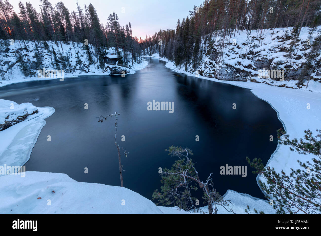 I boschi innevati incorniciato da acqua congelata e luci blu del crepuscolo Juuma Myllykoski Lapponia Regione Finlandia Europa Foto Stock