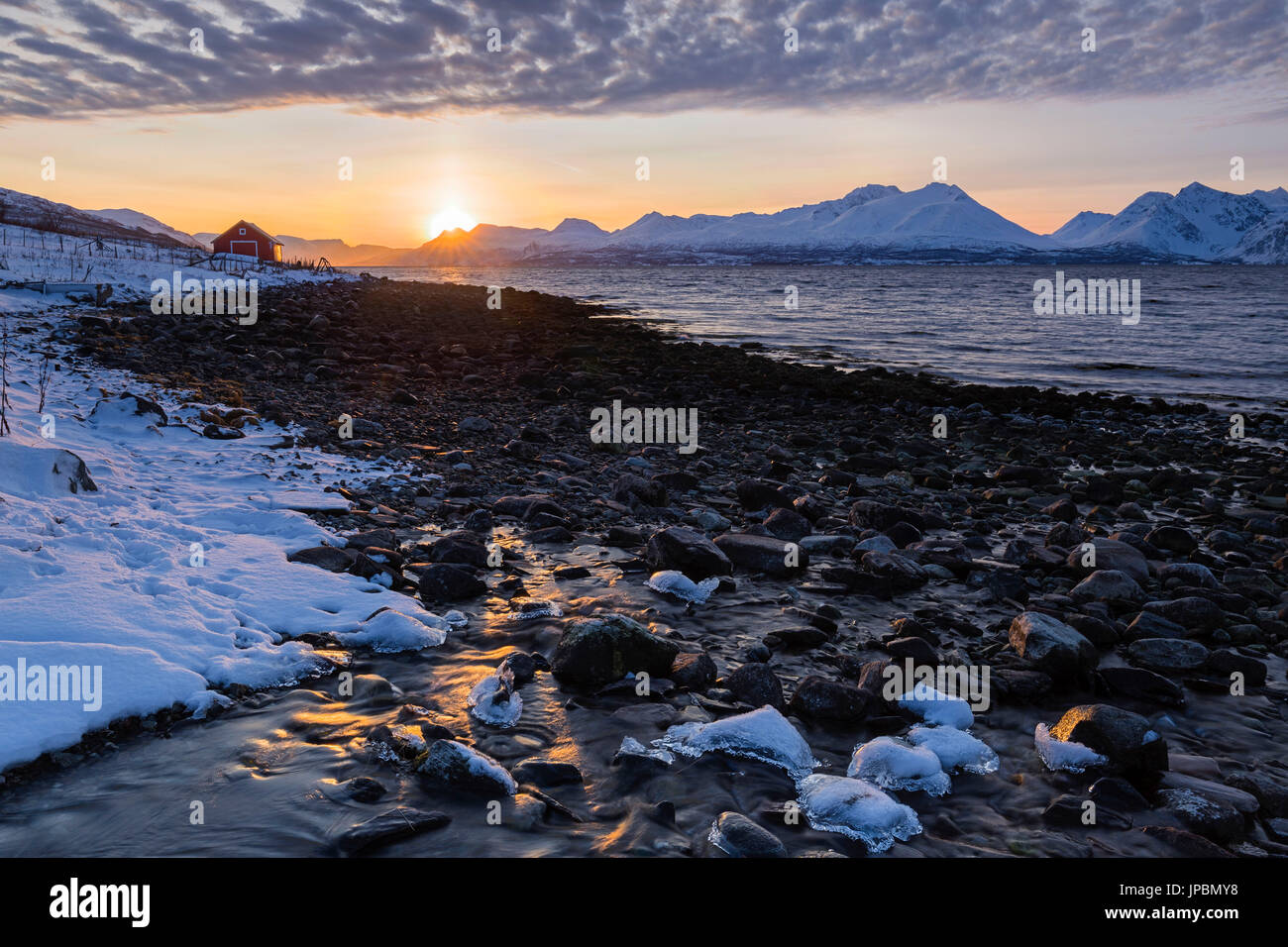 Il sole tramonta dietro le Alpi Lyngen. Nordmannvik, Kafjord, Alpi Lyngen, Troms, Norvegia, Lapponia, l'Europa. Foto Stock