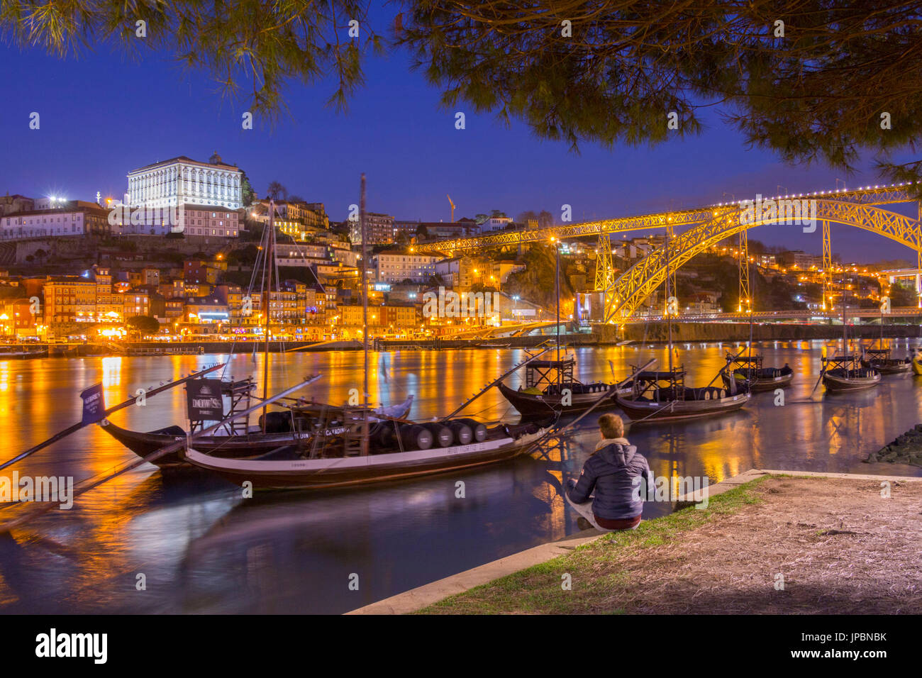 L'uomo guarda il porto e il vino barche sul fiume Douro. La città di Oporto, Distretto di Porto, Portogallo, Europa Foto Stock