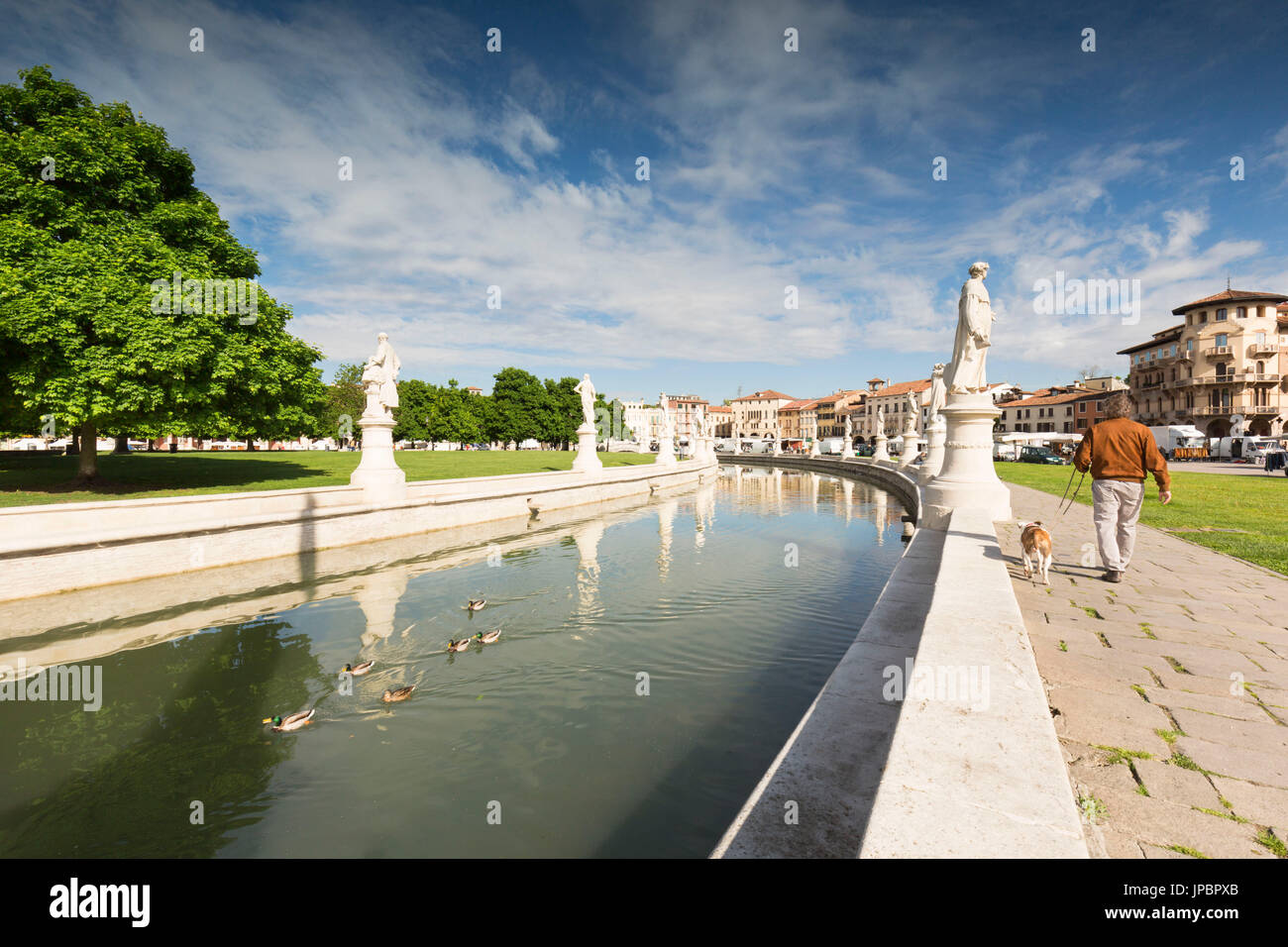 Un dettaglio del Prato della Valle, con il suo tipico canale circolare e un uomo con il suo cane a camminare intorno ad esso, della provincia di Padova, Veneto, Italia, Europa Foto Stock