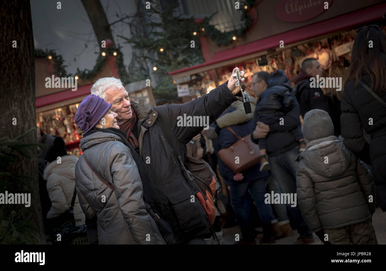 Un vecchio paio di scattare una istantanea durante il tradizionale mercatino di Natale a Bolzano in provincia di Bolzano, Alto Adige, Trentino Alto Adige, Italia, Europa Foto Stock