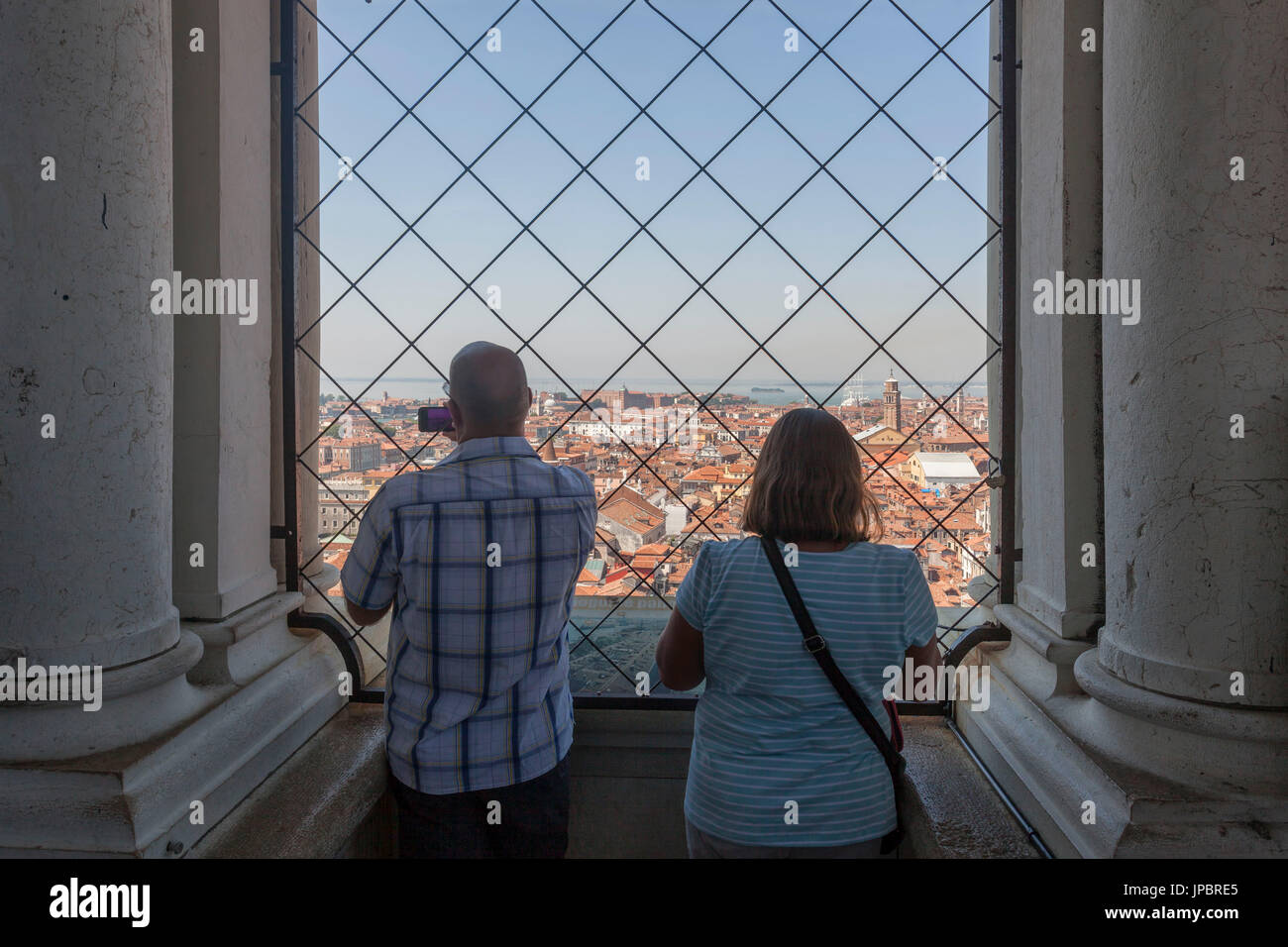 Coppia di turisti a guardare e fotografare la vista di Venezia dal San Marco torre campanaria. Veneto, Italia Foto Stock