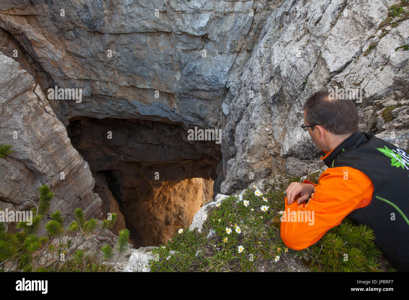 Europa, Nord Italia, Veneto, Belluno, Monti del Sole, Dolomiti. Escursionista si appoggia sul bordo della impressionante Bus de le Neole (foro di nuvole) Foto Stock