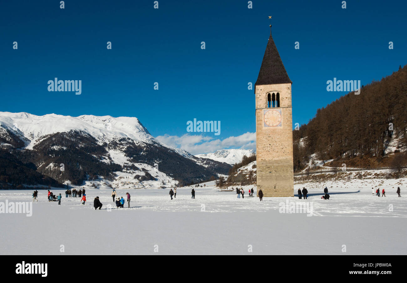 Il campanile della chiesa vecchia del Comune di Curon Venosta, ora sotto il lago di Resia in inverno, con il lago congelato e coperto di neve, Trentino Alto Adige, Italia Foto Stock