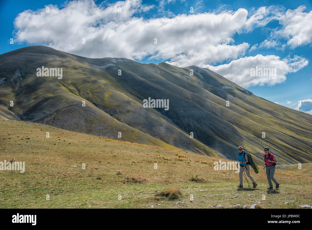 Gli escursionisti sul pianoforte grande altopiano con monte Vettore sullo sfondo, estate, cielo blu con nuvole, Dolomiti, Veneto, Italia Foto Stock