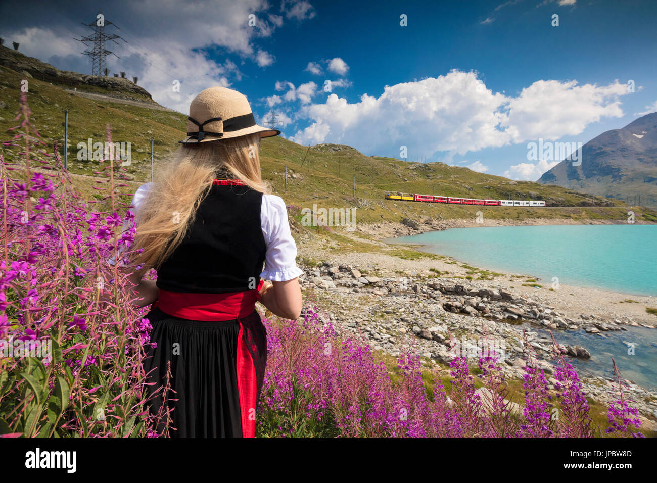 Donna con abiti tradizionali si ammira il trenino rosso presso il Lago Bianco del Bernina Cantone dei Grigioni Engadina Svizzera Europa Foto Stock