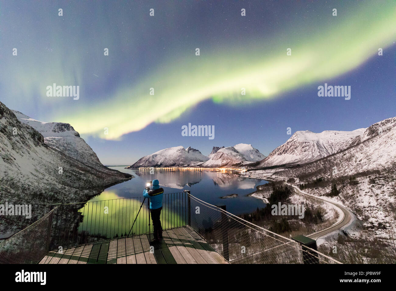 Fotografo sulla piattaforma ammira le luci del nord e stelle si riflette nel mare freddo Bergsbotn Senja Tromsø Norvegia Europa Foto Stock