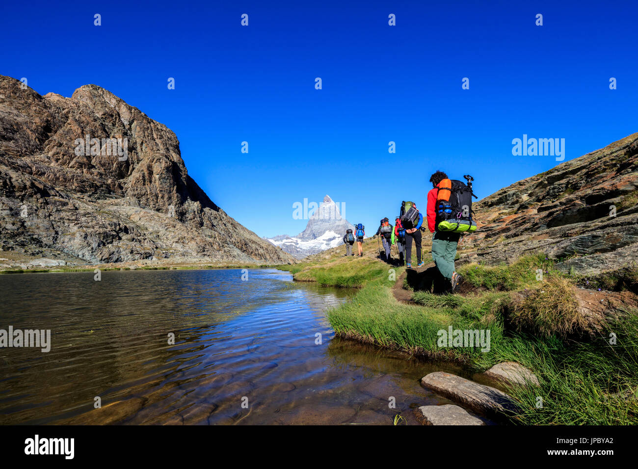 Gli escursionisti procedere sulla riva del lago Riffelsee con il Cervino sullo sfondo Zermatt Cantone del Vallese Svizzera Europa Foto Stock