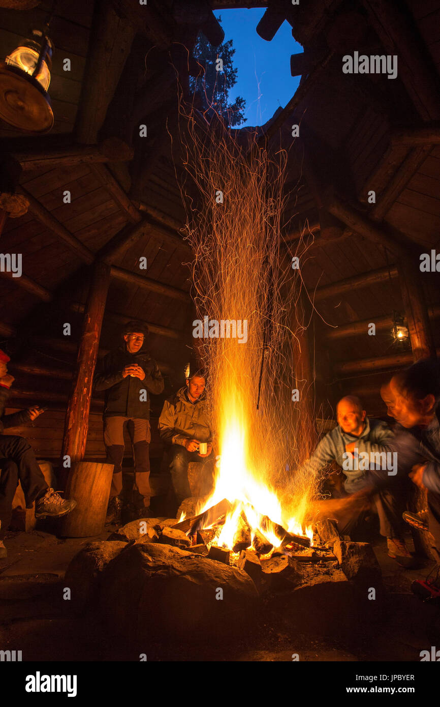 Gli escursionisti riscaldarsi intorno al fuoco a Brandheia Wilderness Camp Trøndelag Norvegia Europa Foto Stock