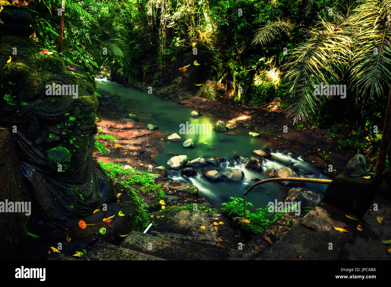 Cascata segreto nascosto nella giungla tropicale con tradizionale antica statua di pietra su uno scenario di sfondo natura Foto Stock